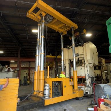 Large yellow hydraulic lifting machine in an industrial workshop.