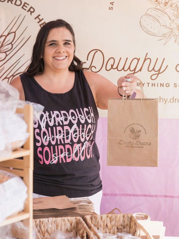 Smiling woman holding a paper bag at a bakery stall.