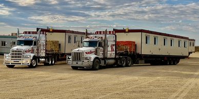 Two trucks transporting large modular buildings.