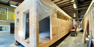 Wooden structure being built indoors in a factory.