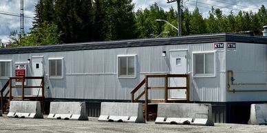 Portable office trailers with stairs and barriers outside.