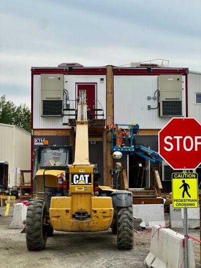 Construction site with a CAT vehicle and workers near a building.