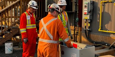 Three workers in safety gear inspecting equipment.