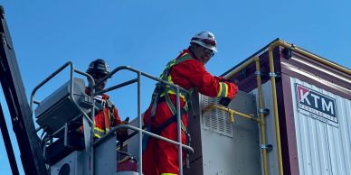 Two workers in safety gear inspecting equipment on a platform.