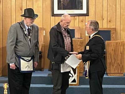 Three men in formal attire at a ceremony.