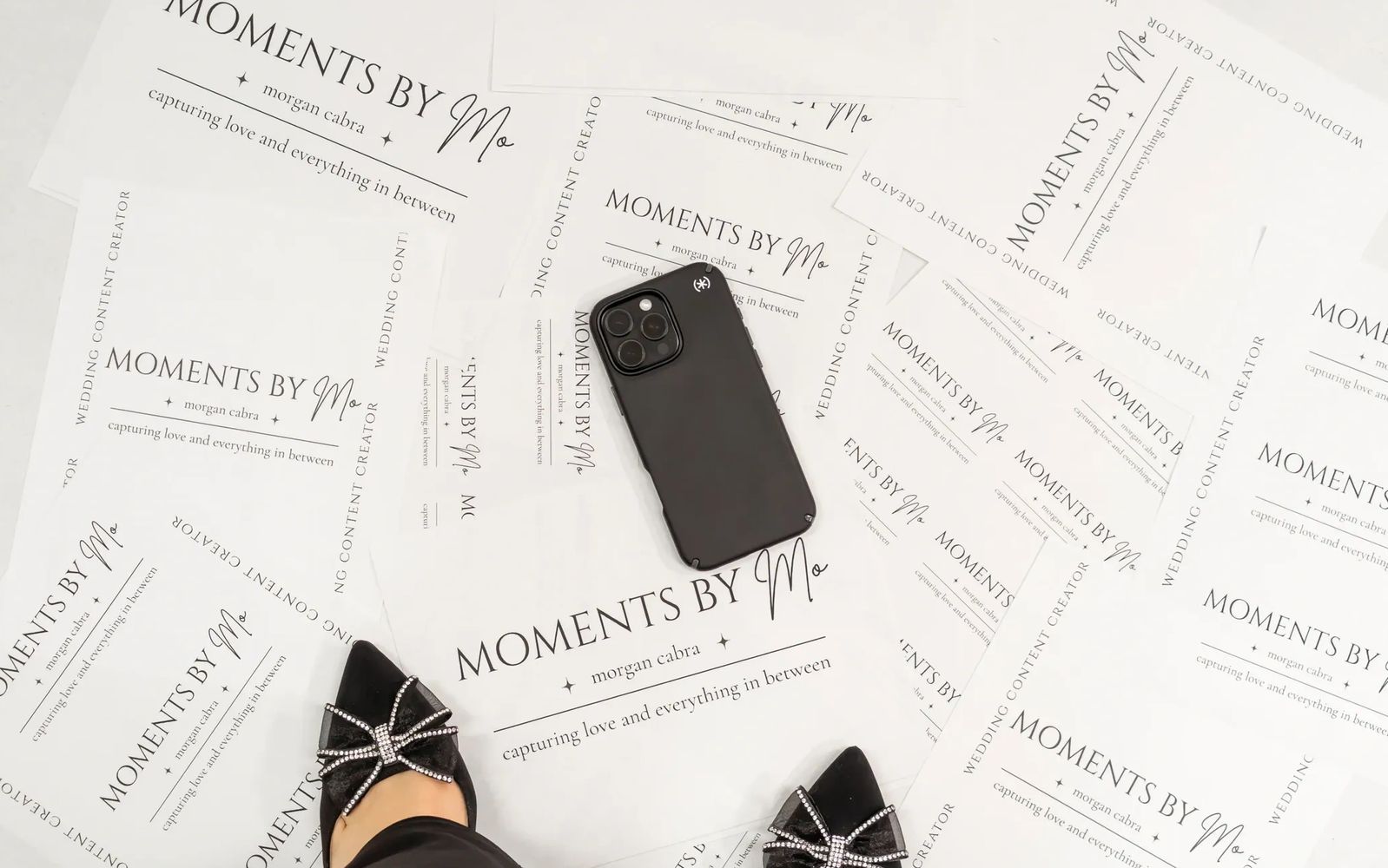 Black phone on wedding content creator papers with stylish black shoes.