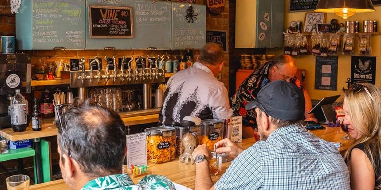 People enjoying drinks at a cozy, warmly lit bar with eclectic decor.
