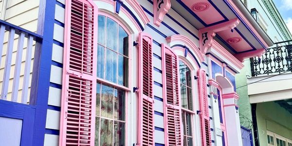 Colorful house with pink shutters and blue striped walls under a clear sky.