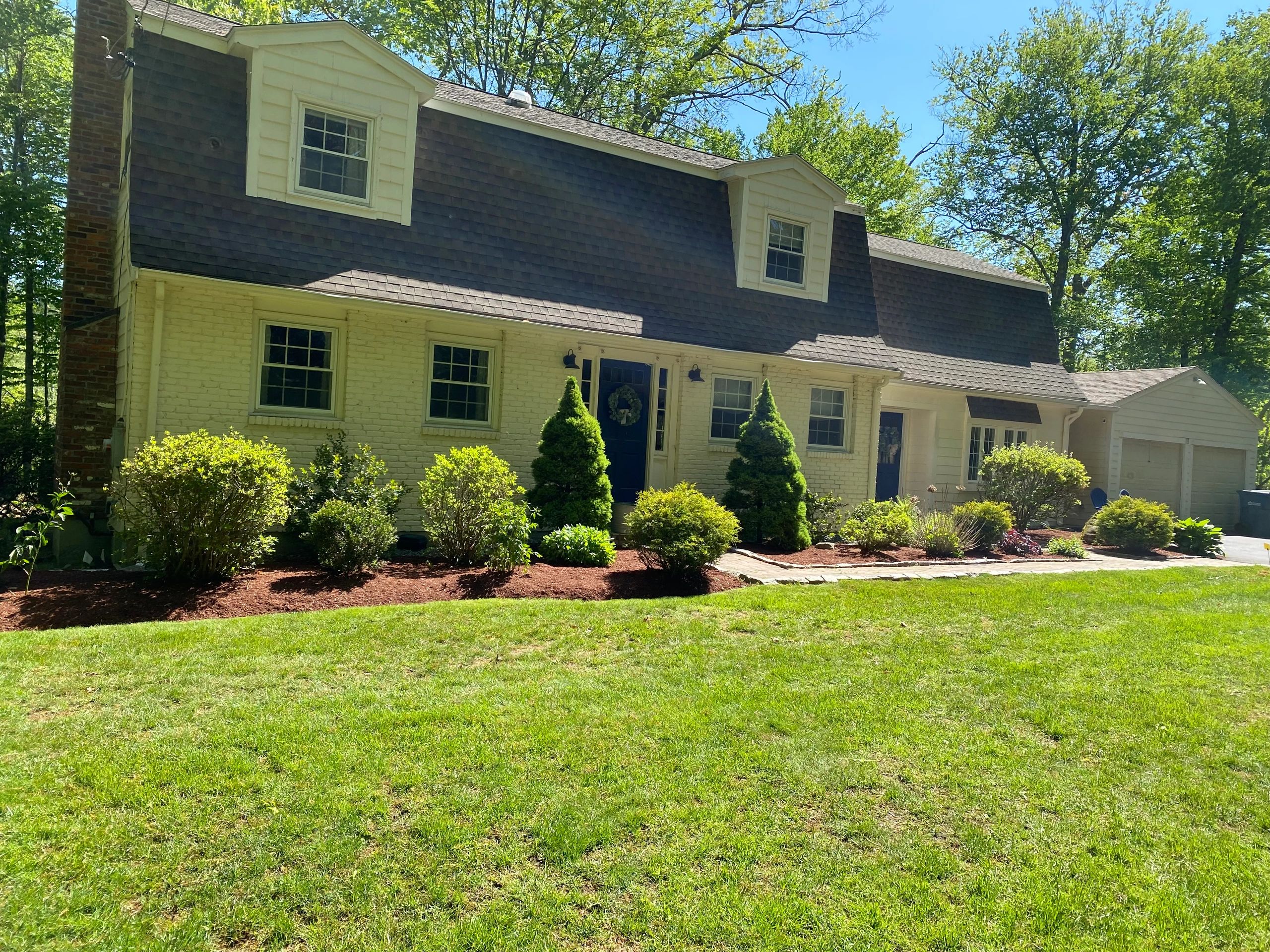 House with clean beds and clean lawn where all  the lawn debris have been removed.