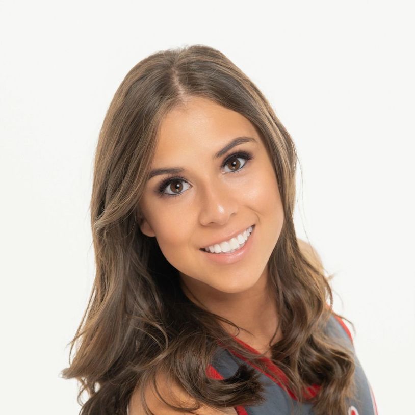 Young woman with long brown hair smiling warmly at the camera.