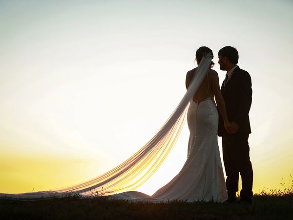 A couple wearing wedding outfit standing while watching the sunset