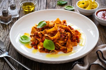 A plate of creamy pasta garnished with basil 