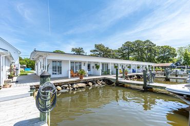 Waterfront house with a dock and boats under a clear sky.