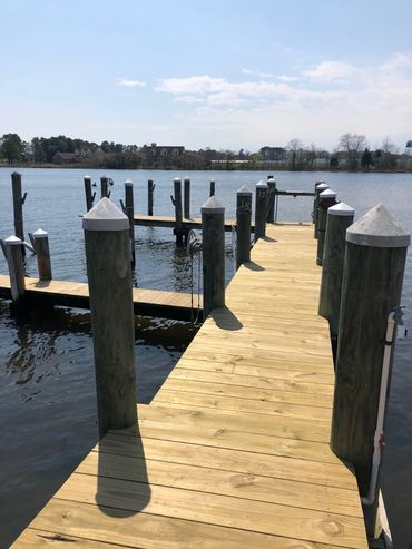 Wooden dock extending over calm water under a clear sky.