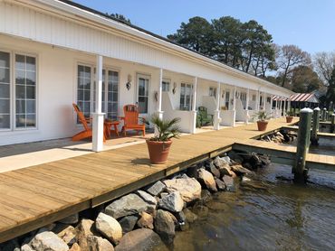 Waterfront motel with outdoor seating and wooden dock.