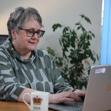 Older woman working on a laptop, smiling.