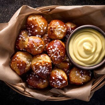 Basket of soft pretzel bites with coarse salt and mustard dip.