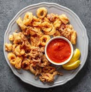 Plate of fried calamari with marinara sauce and lemon wedges.