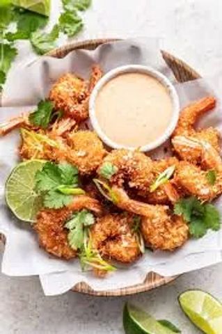 Crispy coconut shrimp with dipping sauce and lime wedges.