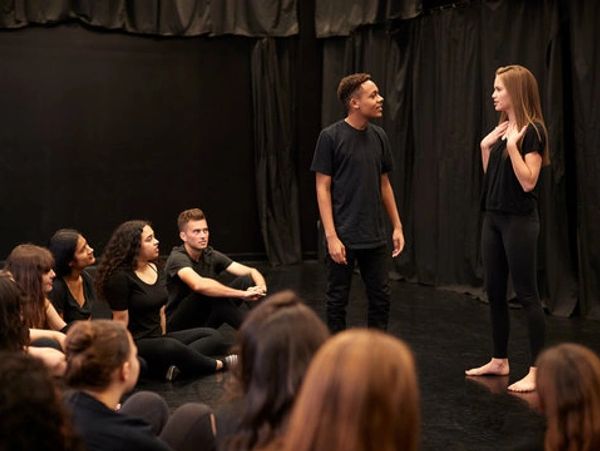 Actors performing on stage with an audience watching.
