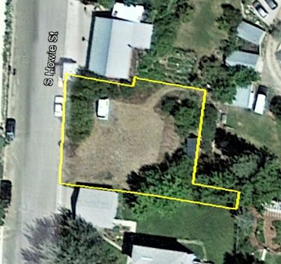Aerial view of a fenced property with a vehicle and trees.