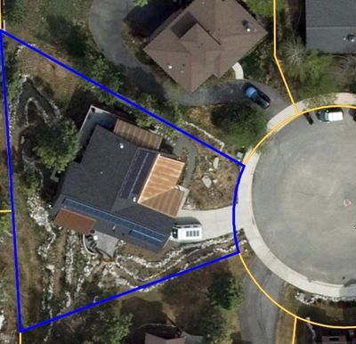 Aerial view of a house with solar panels in a cul-de-sac.