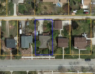 Aerial view of a residential property outlined in blue among neighboring houses.