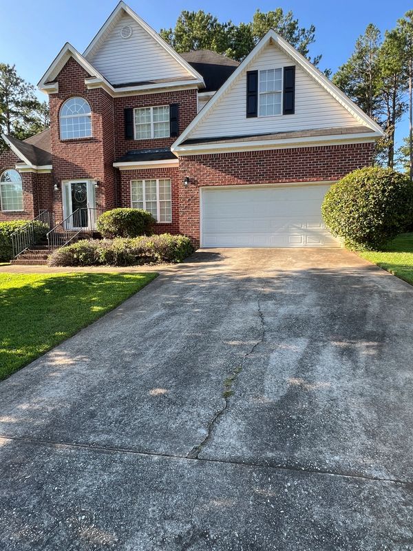 Concrete driveway with dark staining and organic buildup before professional pressure washing in Mac