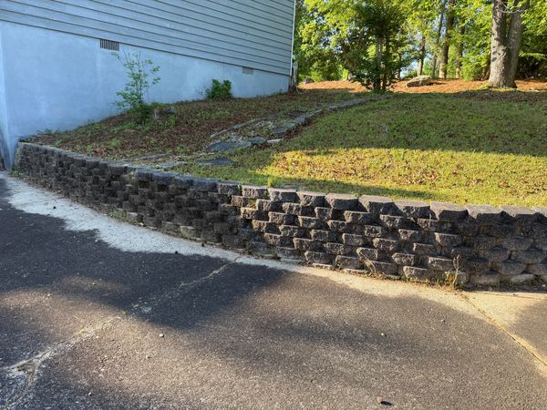 Retaining wall blocks with dark organic buildup before professional exterior cleaning in Macon, GA.