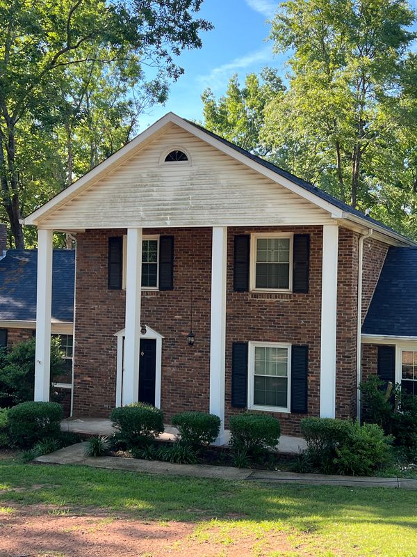 Organic staining on home exterior before professional soft washing in Jones County GA