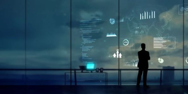 Silhouette of a man analyzing futuristic data projections in an office at dusk.