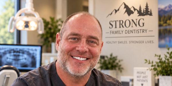 Smiling man in dental office showing healthy teeth.