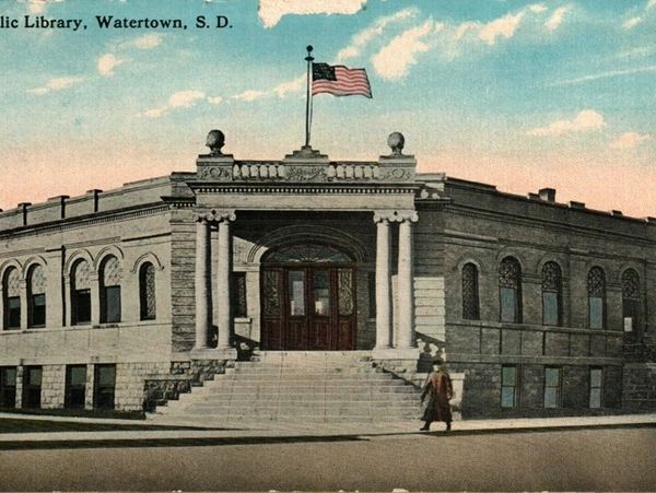 Historic Public Library building in Watertown, South Dakota with American flag.