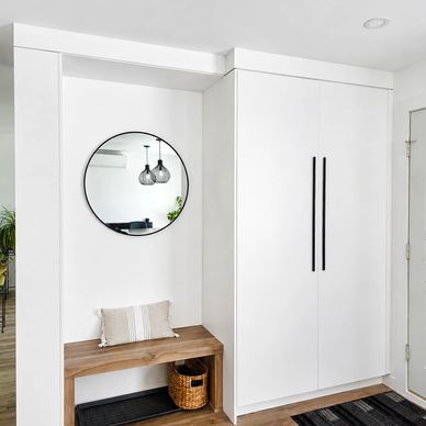Entrée minimaliste avec banc en bois et miroir rond.