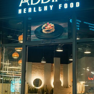 Exterior view of a healthy food restaurant at night with a pancake image.