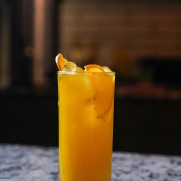 A refreshing orange cocktail garnished with orange slices and ice.