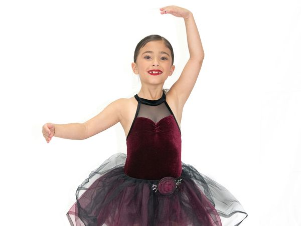 Young girl in a dark purple ballet costume posing gracefully.