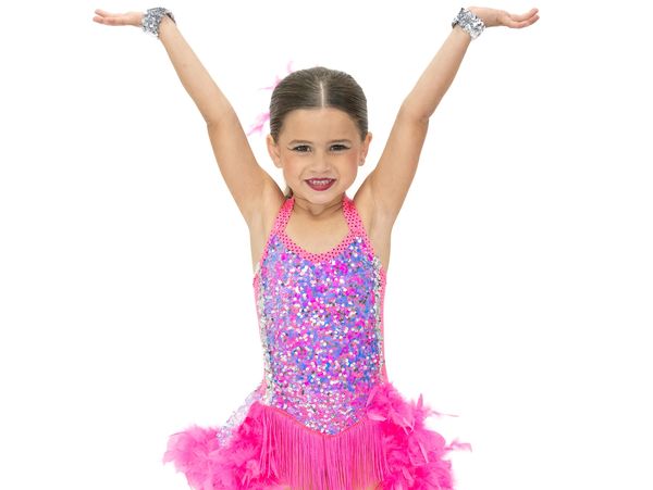 Young girl in a sparkling pink dance costume with arms raised.