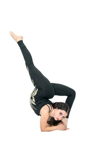 A woman performs an advanced yoga pose with one leg extended upward.