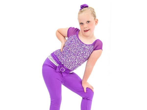 Young girl in a purple dance costume posing confidently.
