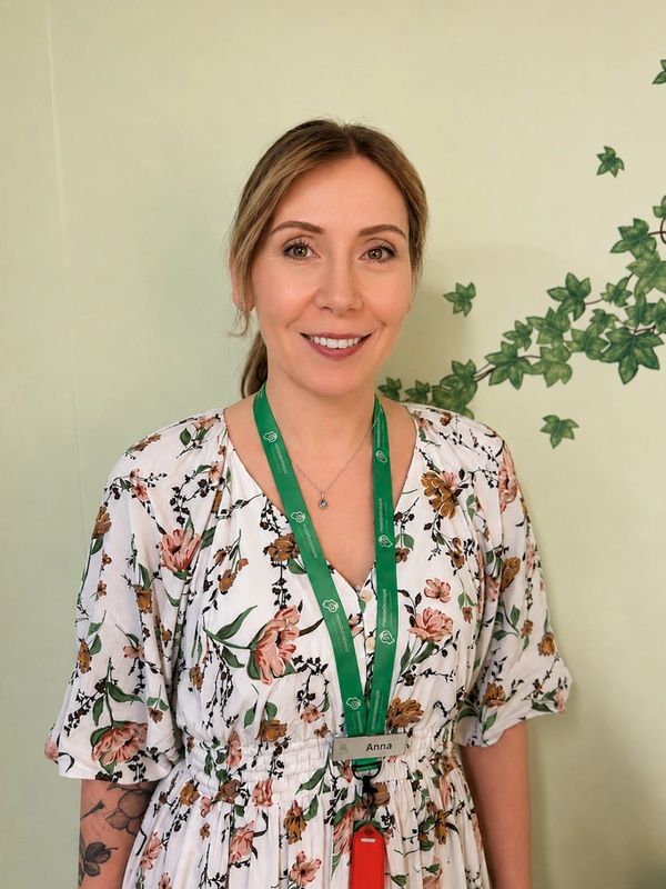 Smiling woman with floral dress and green lanyard.