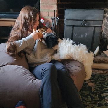 Girl cuddling a small white and black dog indoors.