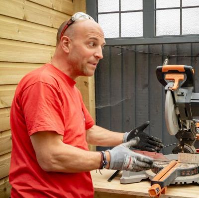 Man explaining near a miter saw in a workshop.