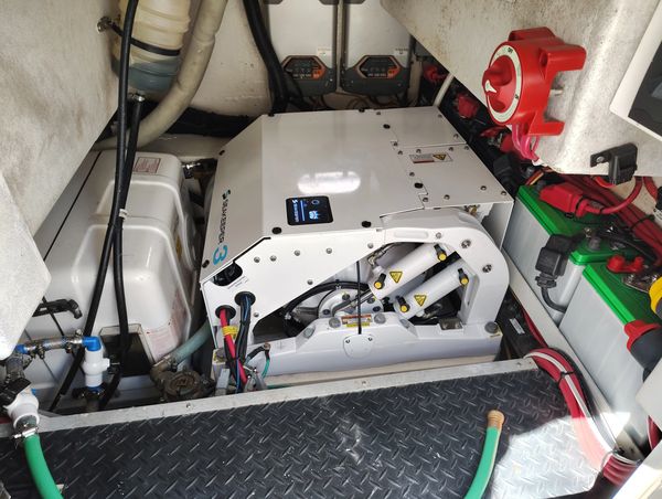 Marine engine room with a white generator and various cables.