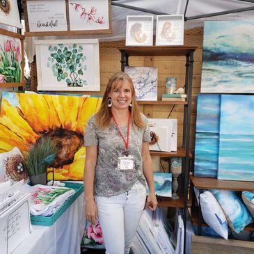 Amy Bunnell Jones standing in front of her artwork at an art show.