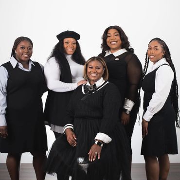A group of five women dressed in black and white outfits.