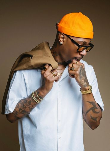 Man wearing orange cap and white shirt with tattoos.