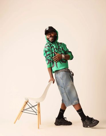 Man in green hoodie leaning on chair and smiling.