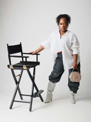 Stylish woman posing next to a black director's chair.