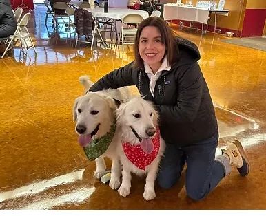 Woman smiling with two dogs inside a building.